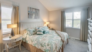 A bedroom with a bed, two bedside tables, a nightstand, a lamp, and a window with curtains. - Coastal St Simons Retreat Near Gascoigne Bluff! (St Simons Island)