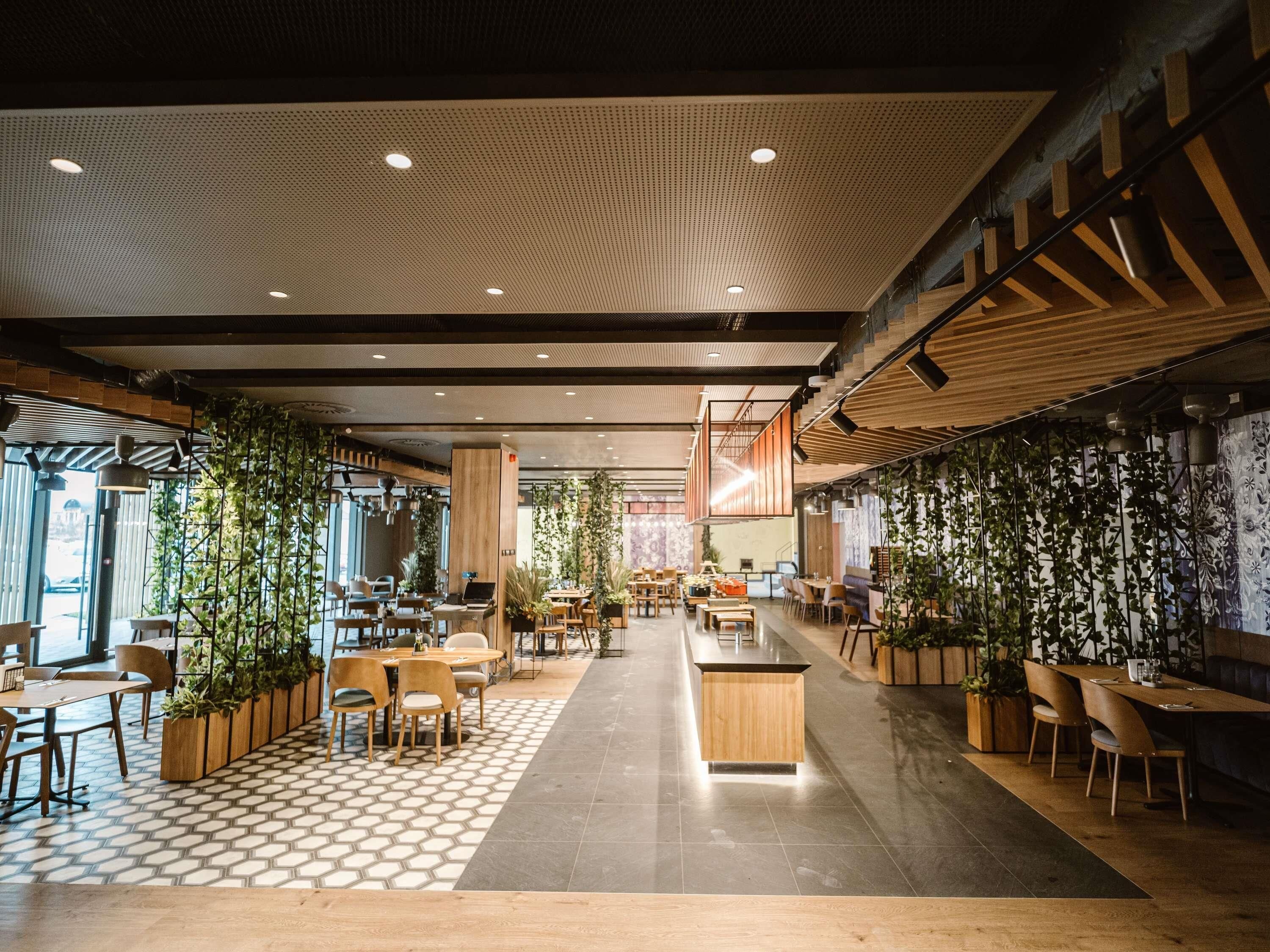 A modern indoor space with a mix of seating areas, including tables and chairs, and a central counter.