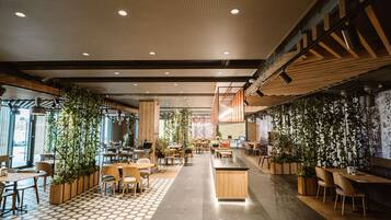 A modern indoor space with a mix of seating areas, including tables and chairs, and a central counter.