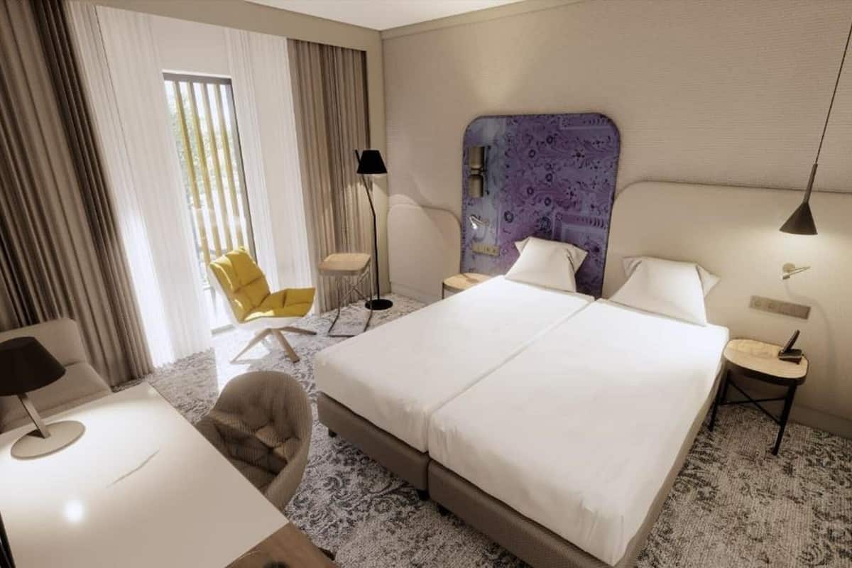 A hotel room with a large bed, a chair, a desk, and a lamp.