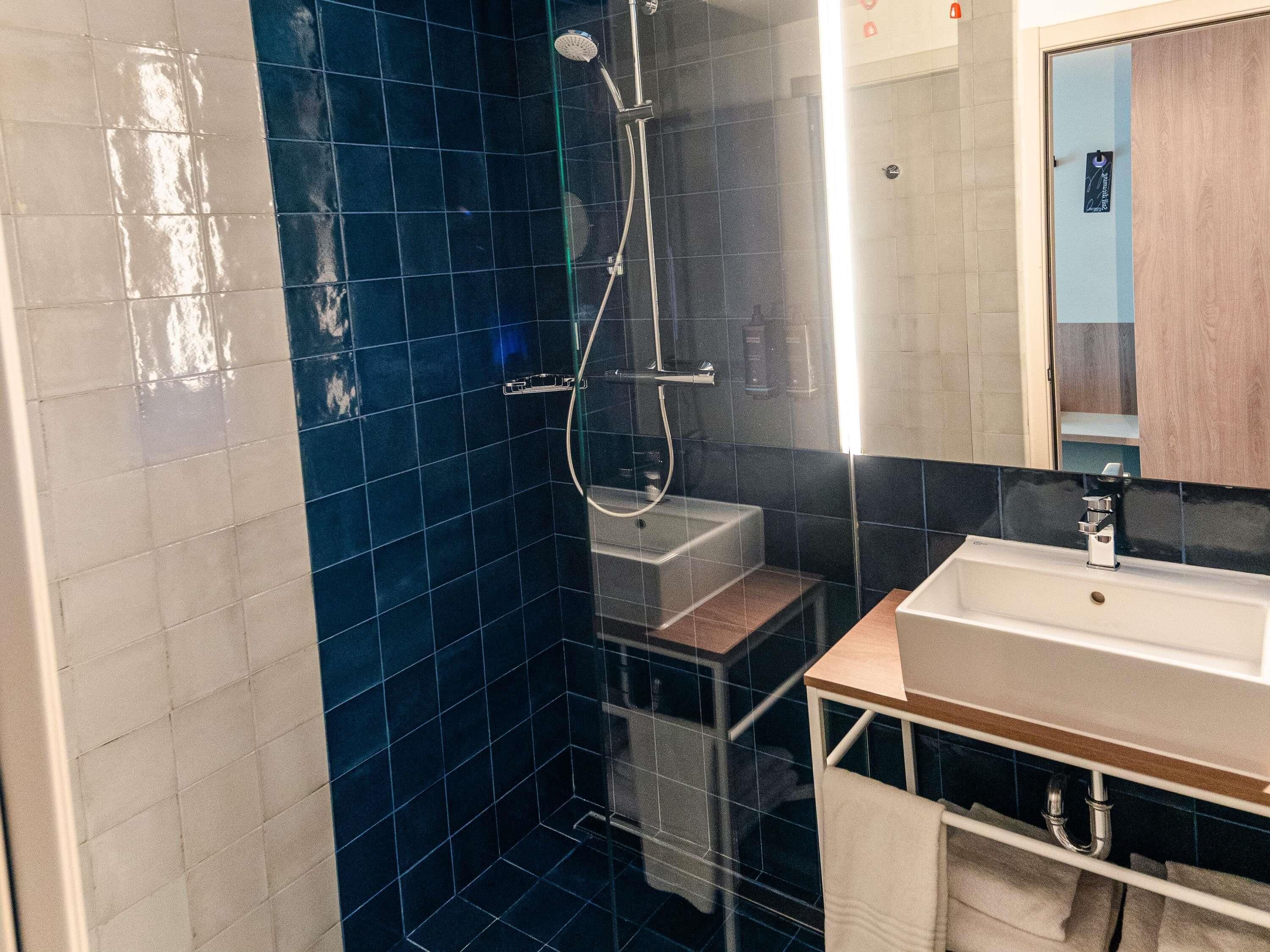 A bathroom with a shower, a sink, and a mirror.
