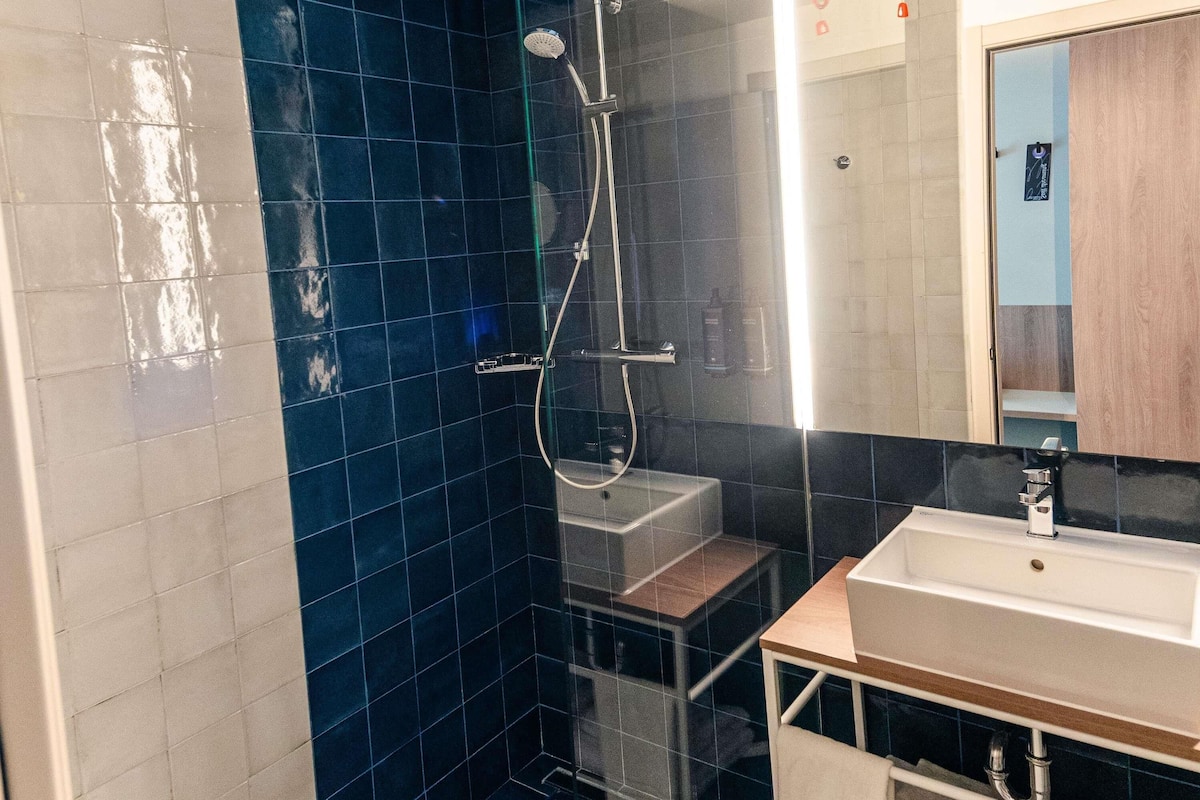 A bathroom with a shower, a sink, and a mirror.