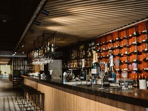 A bar area with a wooden counter, wine bottles, and glasses. - Mercure Sibiu Arsenal (Sibiu)