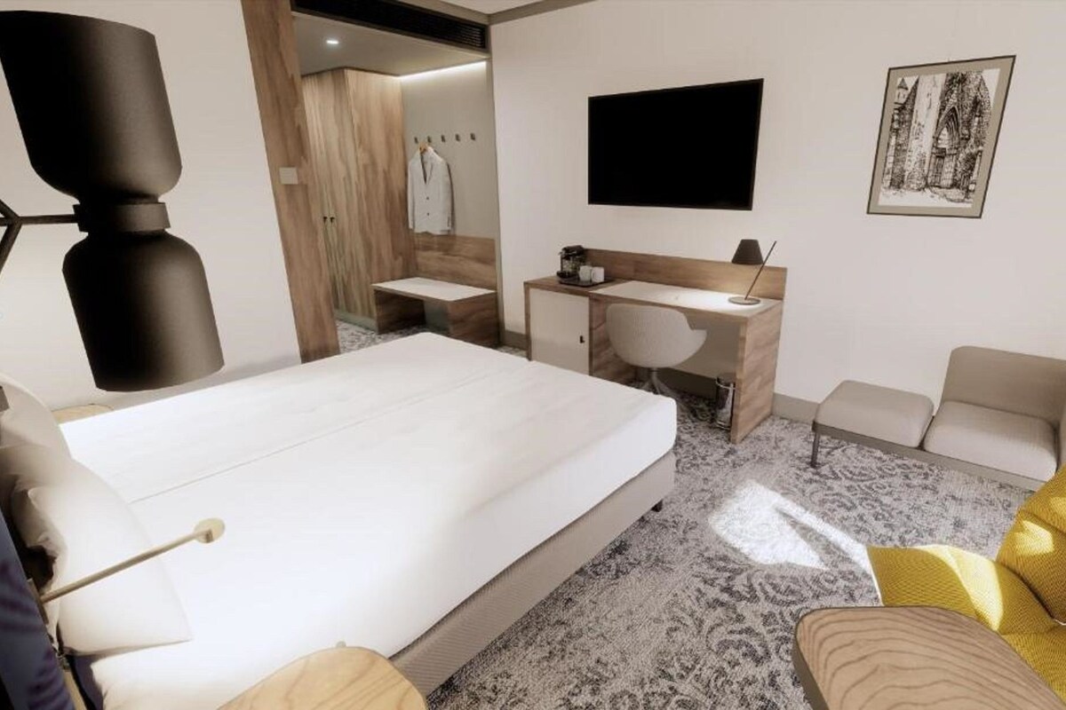 A hotel room with a bed, a desk, a chair, a sofa, a TV, and a painting on the wall.