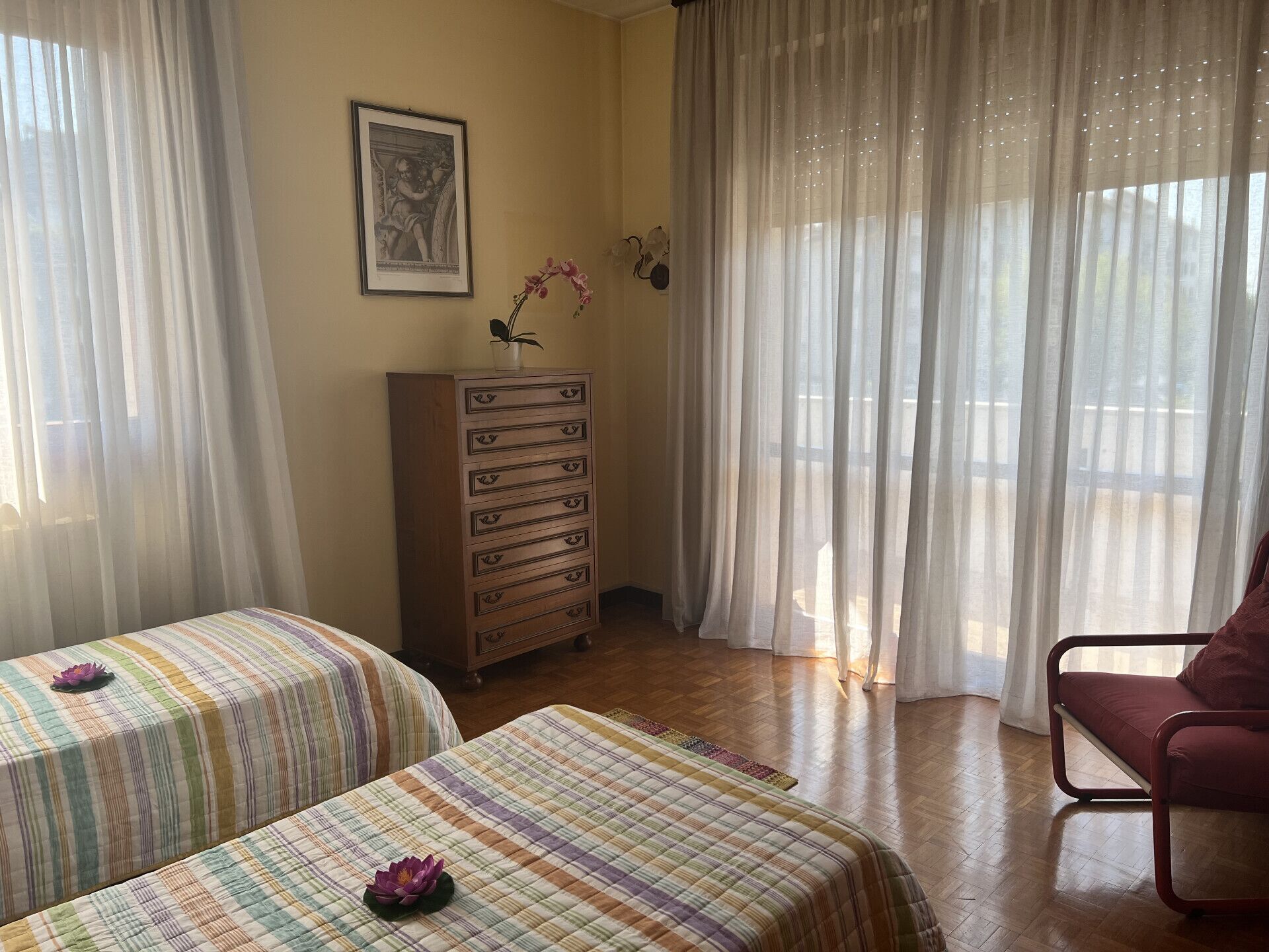 A room with two beds, a wooden dresser, and a chair.