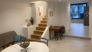 A modern living room with a staircase, a dining area, and a view through a large window. - Large refurbished house in central village location (Dompierre-sur-Mer)