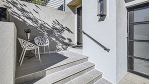 A modern building with a staircase leading to a door, two white chairs, and a small table on the landing. - Luxurious Rental with Ideal Downtown Proximity - Stroll to Pearl Street and CU. (Boulder)