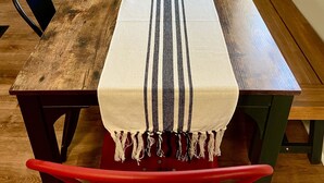 A dining table with a long table runner, chairs, and a window with a view of trees. - Jewel Brook Cottage- 4BR house on a tranquil flowing brook!  (Ludlow)