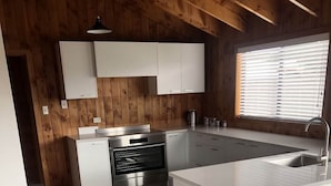 Una cocina moderna con armarios blancos, horno de acero inoxidable y una isla grande con taburetes de bar.