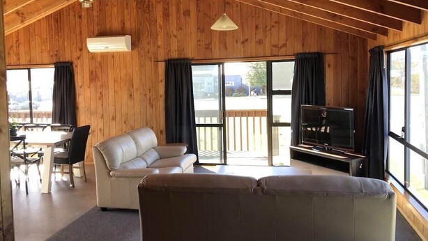 Amplia sala de estar con sofá, televisor y comedor con sillas y mesa.