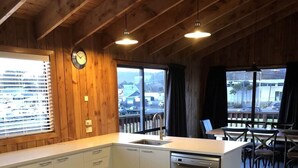 Una cocina con paredes de madera, lavavajillas y comedor con mesas y sillas.
