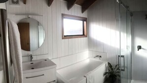 Un baño con tocador blanco, bañera y cabina de ducha.