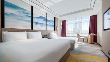 Una habitación de hotel con dos camas, un escritorio y un amplio ventanal con cortinas.