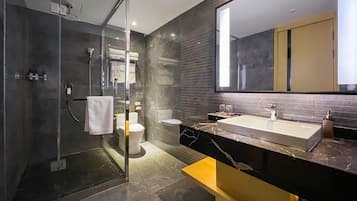 A modern bathroom with a glass shower enclosure, a toilet, and a sink with a marble countertop.