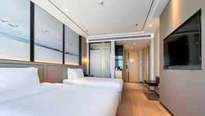 Una camera d'albergo con due letti, una televisione e vista sul cielo attraverso la finestra.