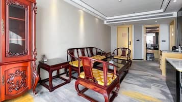 Habitación de hotel con un aparador de madera tradicional, una mesa de comedor con sillas y una cocina moderna al fondo.