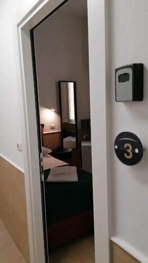 A hotel room with a bed, a bedside table, a mirror, and a wall-mounted number plate. - H22 Hotel (Naples)