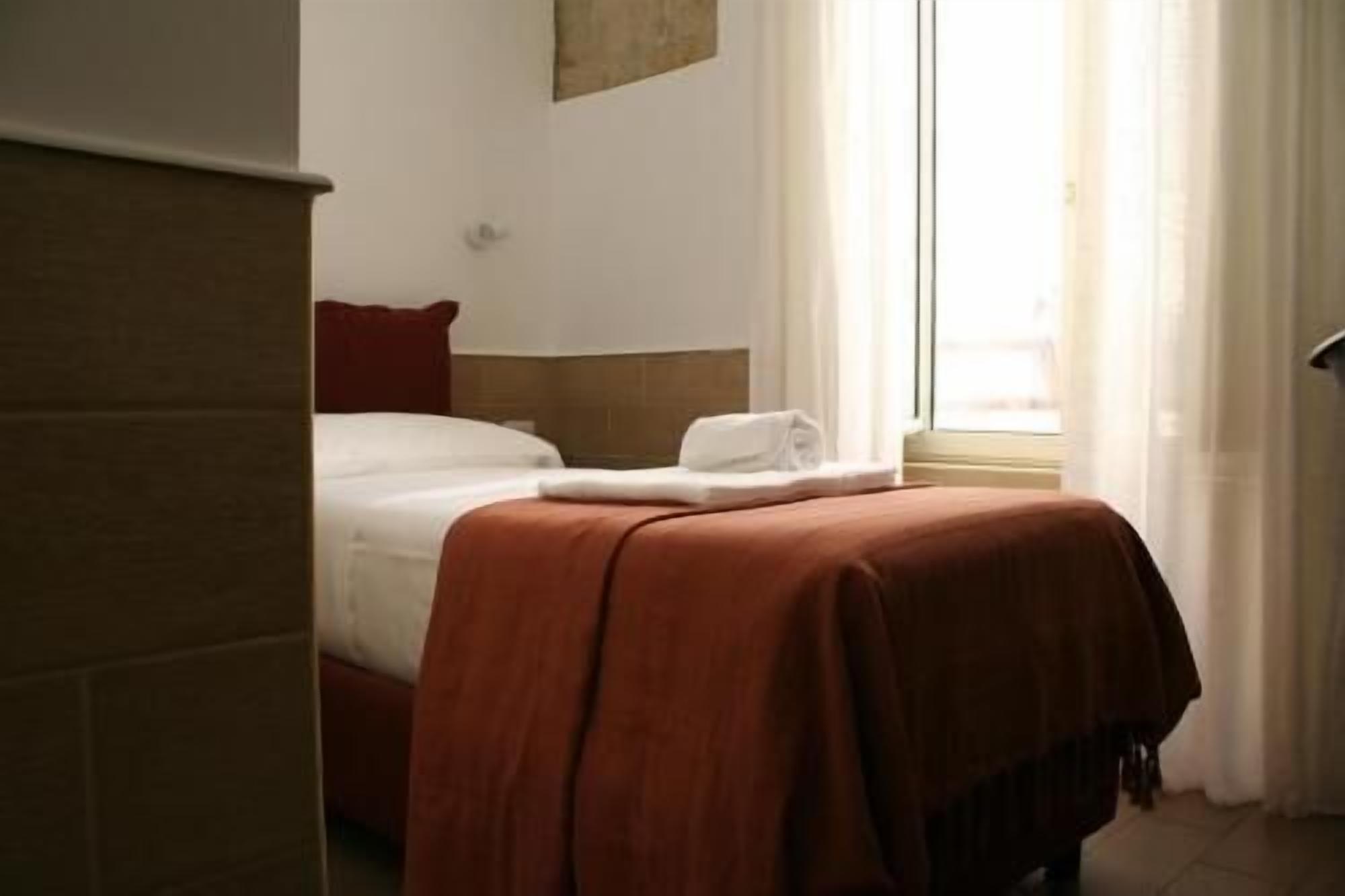 A hotel room with a bed, a window with curtains, and a wall-mounted artwork.