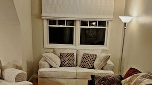 A living room with a sofa set, a patterned rug, and a window with blinds. - Secluded in The Woods (Dana)