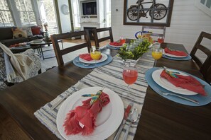 A dining table set with plates, cutlery, and glasses, with a decorative centerpiece and a bicycle-themed wall art piece. - Oceanside - Dog Friendly - 3pm Checkout (Pacific Beach)