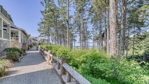 A pathway leading to a building with a porch, surrounded by tall trees and greenery. - Oceanside - Dog Friendly - 3pm Checkout   (Pacific Beach)