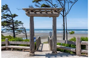 A wooden pergola with a beach view, a sign indicating a 3-minute walk to beach access, and the Seagrass Bluff logo.