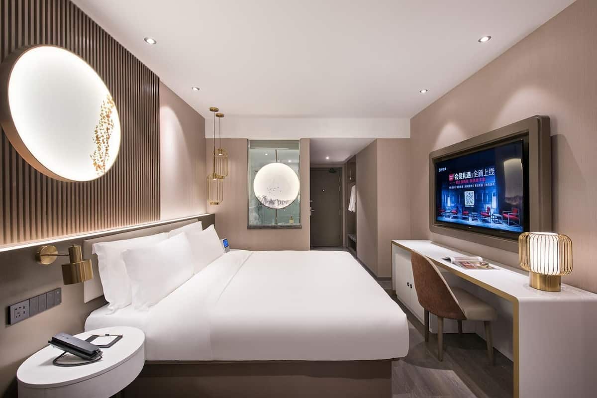Een moderne hotelkamer met een groot bed, een bureau, een televisie en een spiegel.