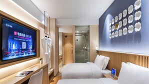 Een moderne hotelkamer met een bed, nachtkastje, televisie en een muur met bloemenprint.
