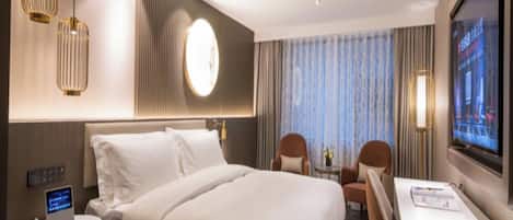 A hotel room with a large bed, bedside tables, a desk, and a TV.