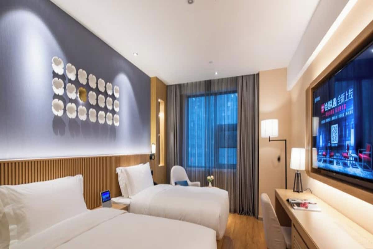 Een hotelkamer met twee bedden, een bureau, een televisie en een wand met decoratieve borden.