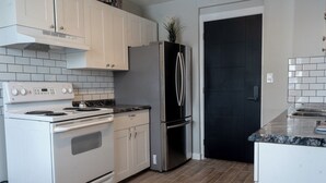 A kitchen with a stove, oven, refrigerator, and cabinets. - One Bedroom Condo Near Whyte Ave (Edmonton)