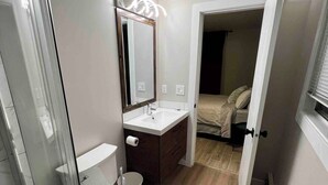 A bathroom with a toilet, sink, and mirror. - One Bedroom Condo Near Whyte Ave (Edmonton)