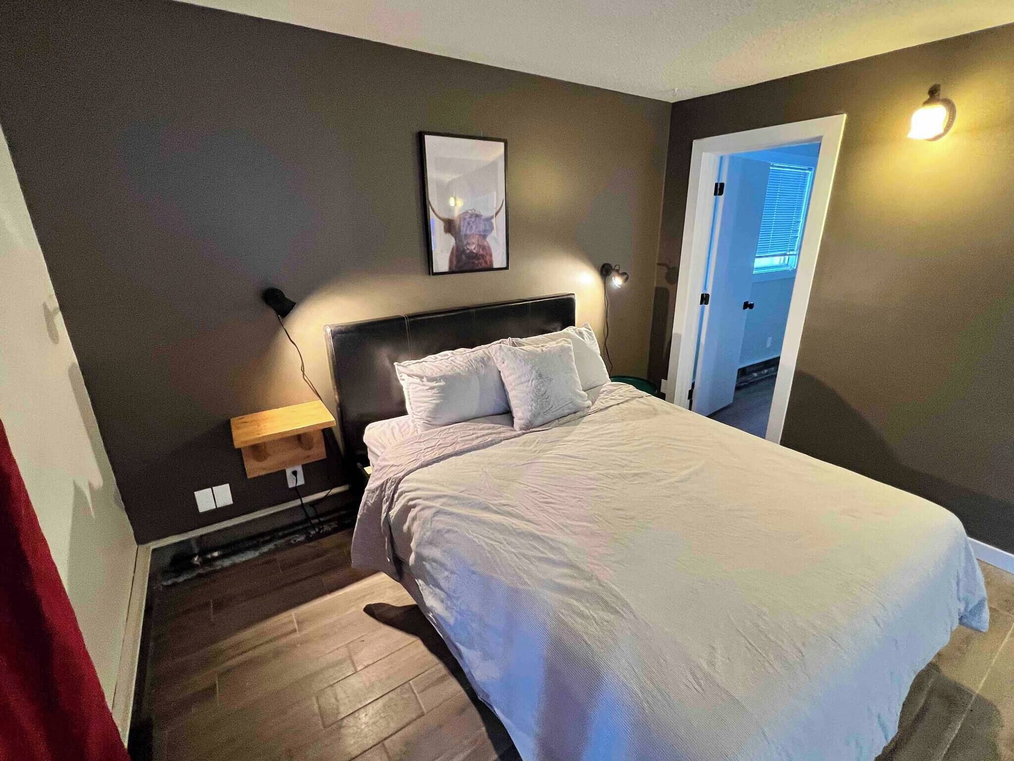 Une chambre à coucher avec un lit, une table de chevet, une lampe et un tableau au mur.