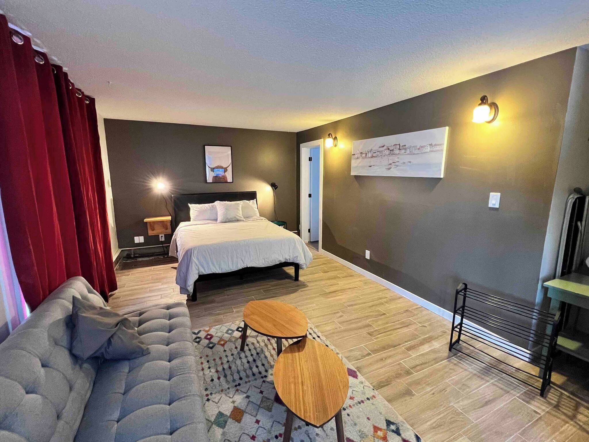 Ein Schlafzimmer mit einem Bett, einer Schlafcouch, einem kleinen Tisch, einem Nachttisch und einer Wandleuchte.