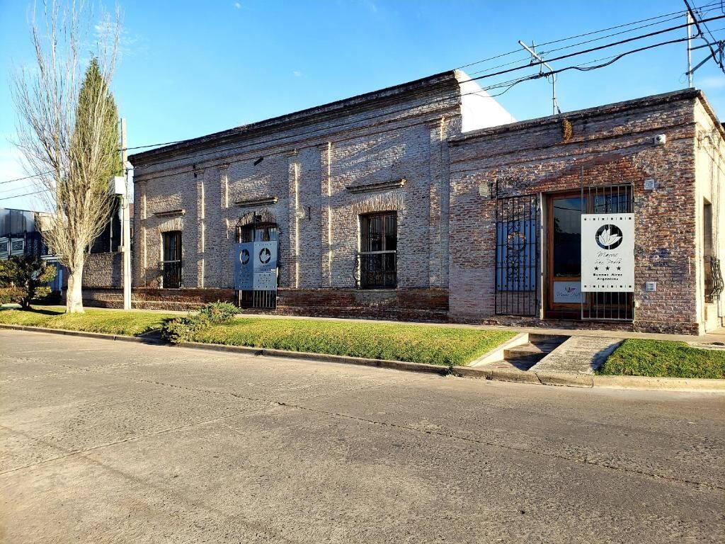 A two-story brick building with a flat roof, large windows, and a signboard on the front.