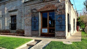 A brick building with a large glass door, a small window, and a metal gate.