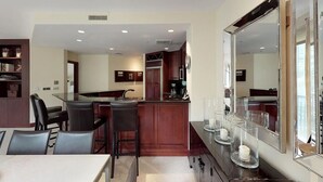 A modern kitchen with dark wood cabinets, a central island, and a dining area with a white table and black chairs. - Liftside 3BR ~Unit C42~ Ski-in-Ski-out Chair #20 (Vail)