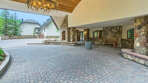A spacious outdoor area with a stone wall, a wooden bench, and a large chandelier. - Liftside 3BR ~Unit C42~ Ski-in-Ski-out Chair #20 (Vail)