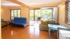 A spacious living room with a blue sofa, a green armchair, and a small table.