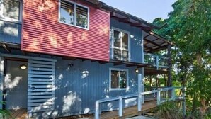 A two-story house with a red and blue exterior, a covered porch, and a small deck.