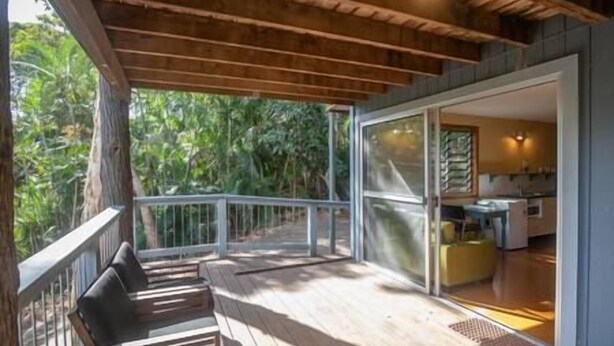 A wooden deck with a glass door leading to a kitchen area.