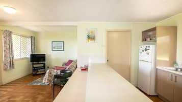 Een knus woongedeelte met een kitchenette, een bank, een televisie en een eethoek.