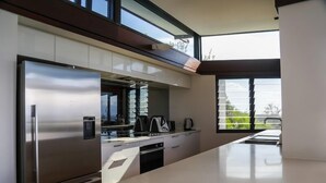 A modern kitchen with a stainless steel refrigerator, a built-in oven, and a large window providing a view of the outdoors. - Banyandah - Breathtaking views (Point Lookout)