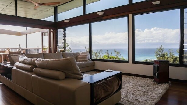 A modern living room with a large window offering a view of the ocean and a balcony. - Banyandah - Breathtaking views (Point Lookout)