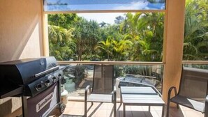 Ein Balkon mit Grill, Tisch und Stühlen mit Blick auf eine üppige, grüne Landschaft.
