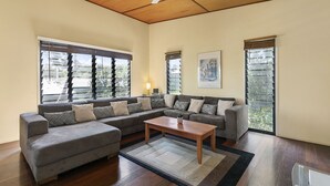 Un salon spacieux avec un grand canapé d’angle, une table basse en bois et un ventilateur de plafond.