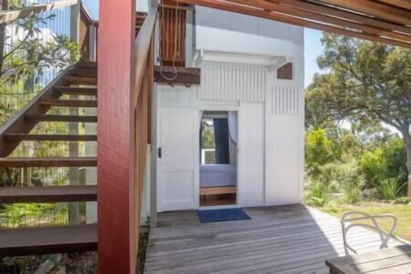 Une terrasse en bois avec une porte donnant sur un espace extérieur abrité.