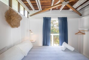 Une chambre à coucher avec un lit, un luminaire suspendu et une vue sur l’extérieur.