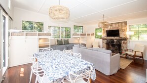 A spacious room with a large table, bunk beds, a sofa, and a fireplace.