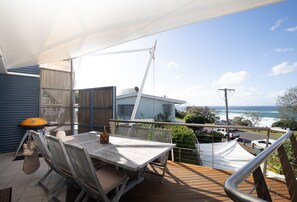 Un balcon avec une table et des chaises, offrant une vue sur la côte.